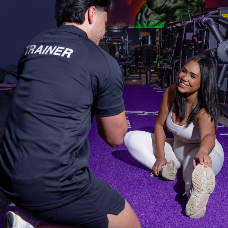 Fitness Cartel Health Clubs personal trainer assisting with clients warmup and stretching session